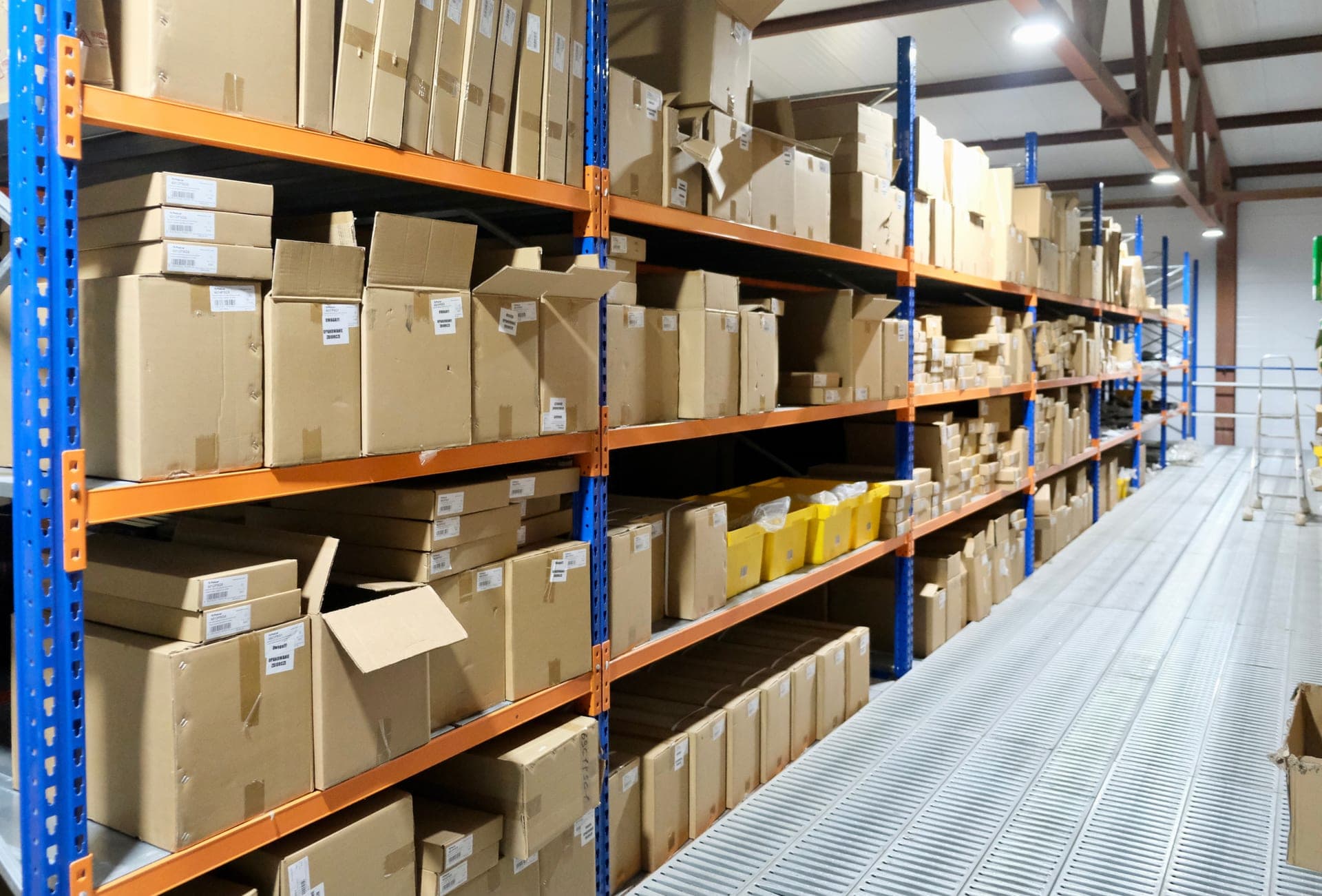 Rows of boxed replacement parts on warehouse shelving, the kind of stock a repair shop draws from