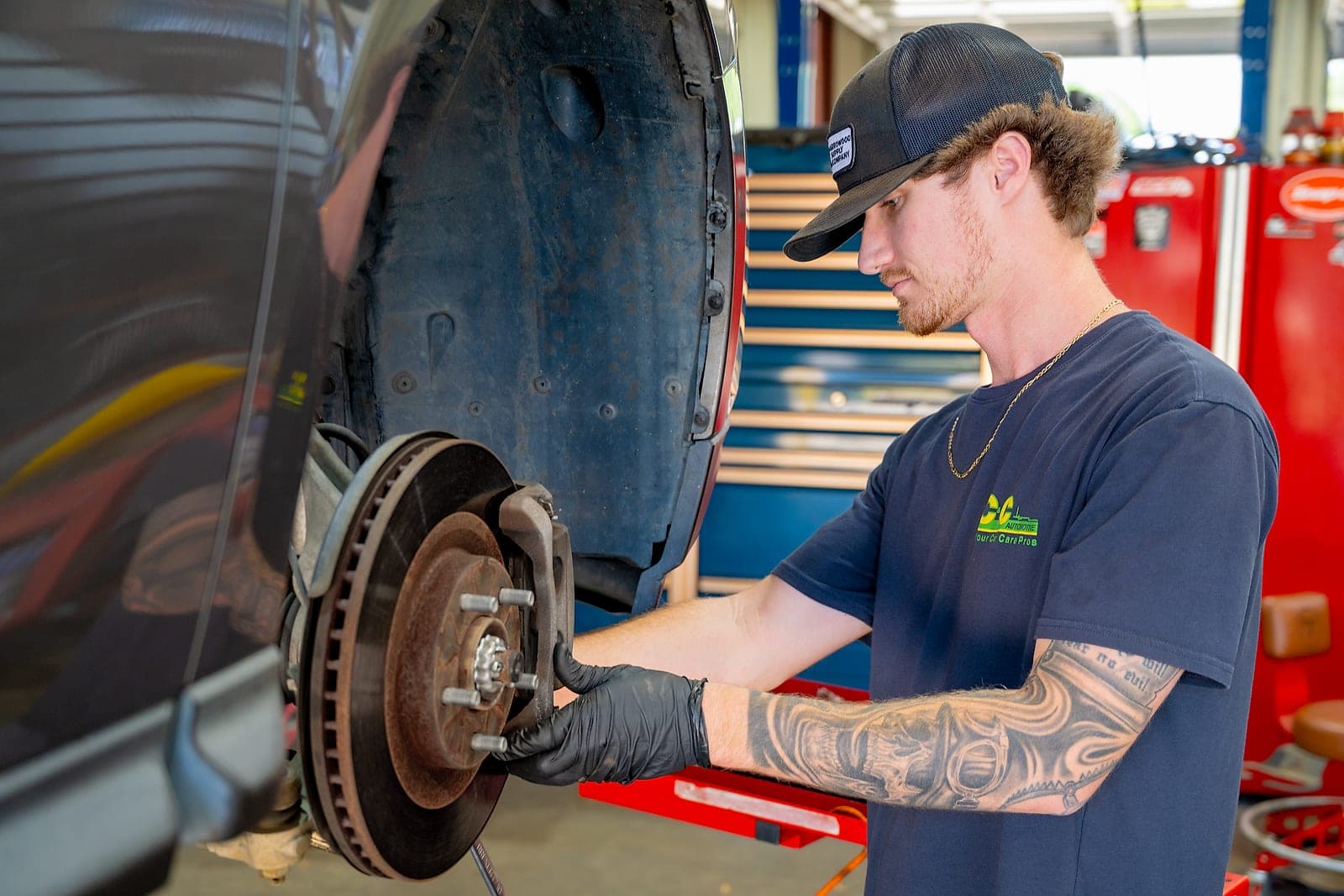 Technician inspecting a brake rotor and caliper during a brake repair at the Thomson service bay.